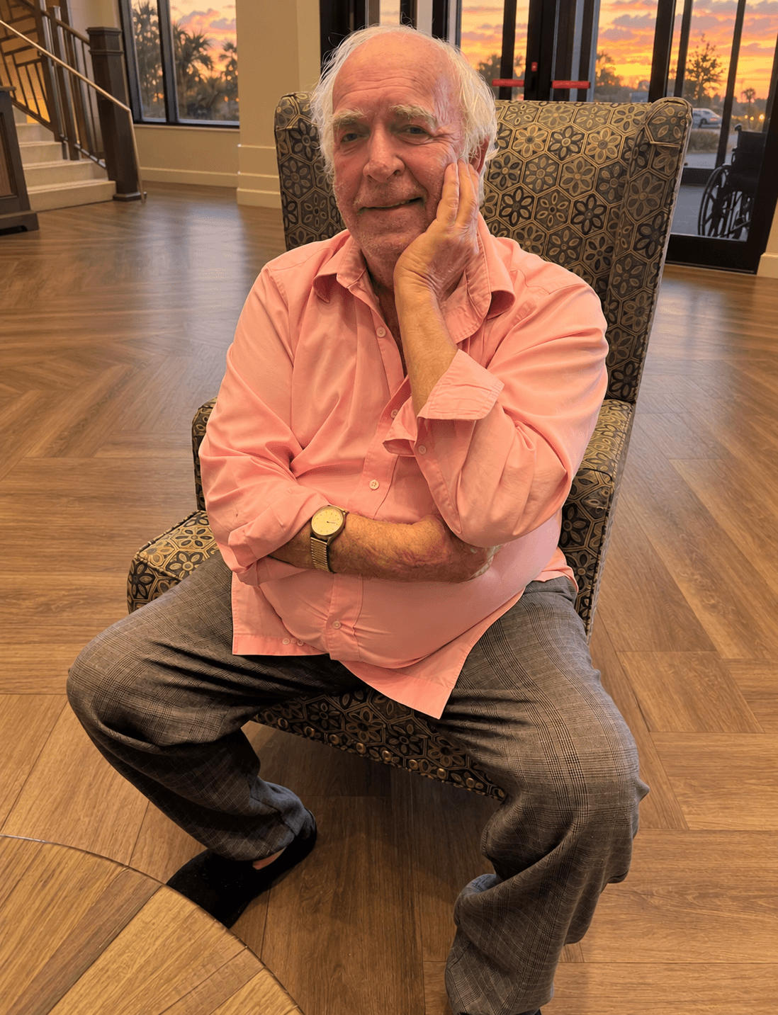 Ray Coppola in a salmon pink shirt sitting in a patterned chair with sunset in background